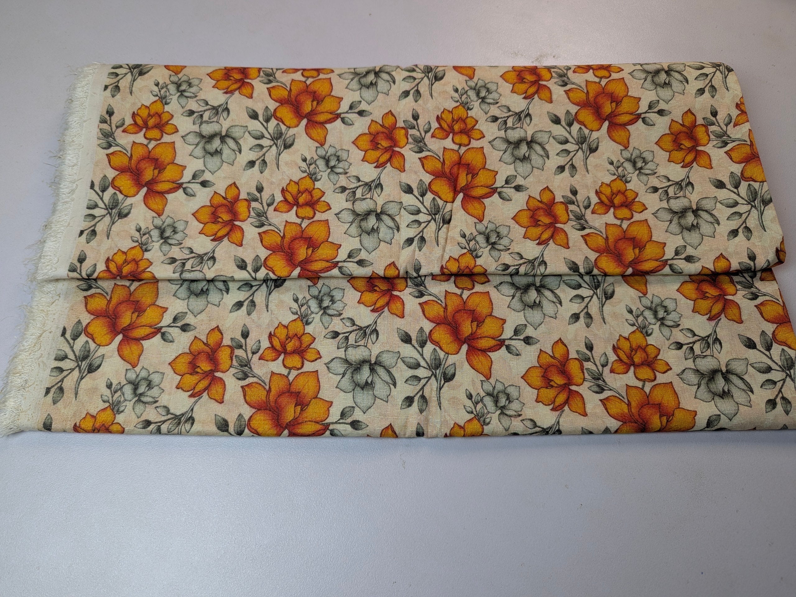 Floral-patterned fabric with orange flowers on a beige background