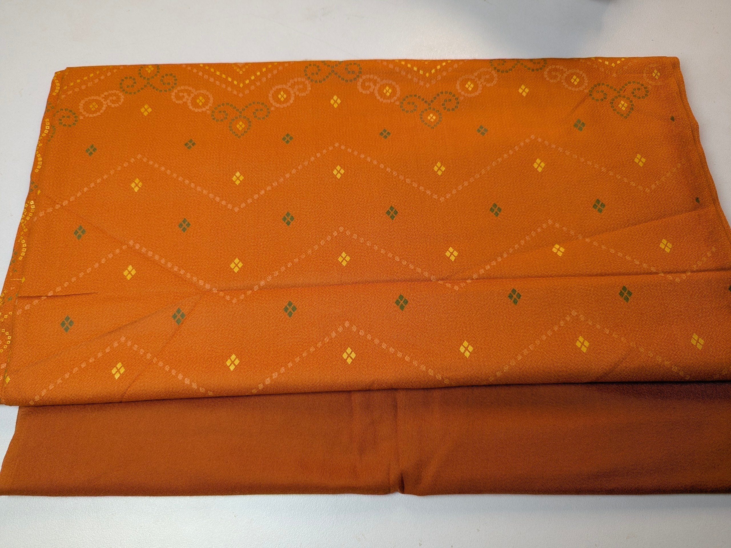Folded orange fabric with geometric patterns on a white background
